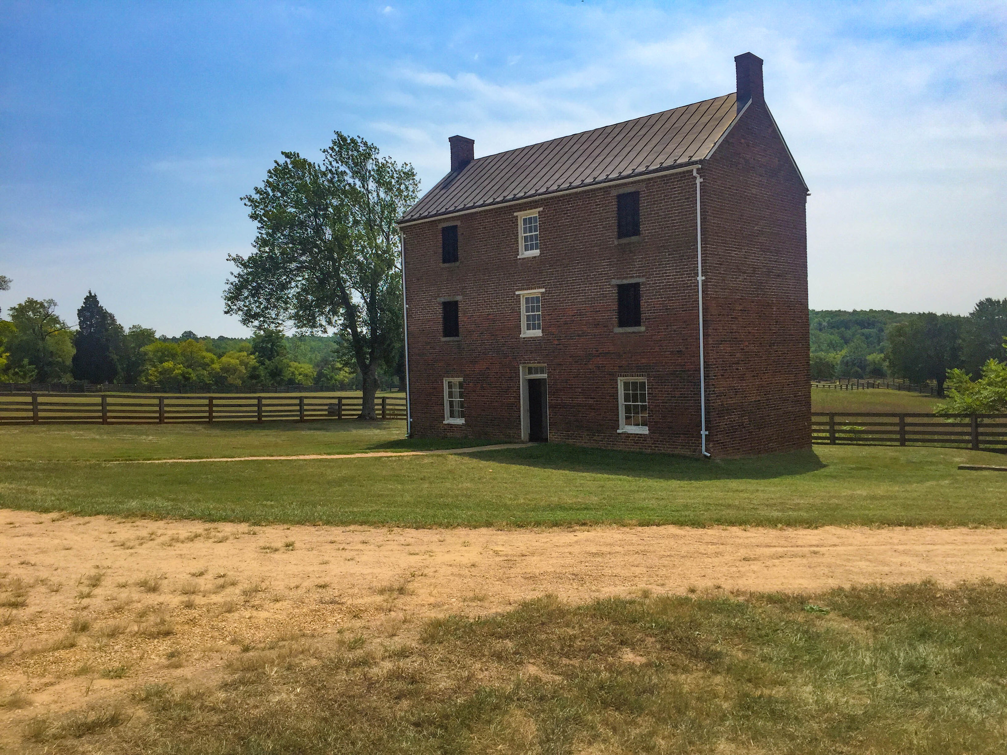 Three story brick building with 4 barred windows, three regular windows and a door on the front of the building which was used for a jail.
