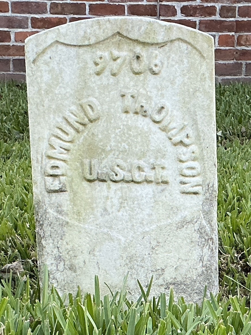 Front of historic upright marble headstone with recessed shield with recessed lettering face.