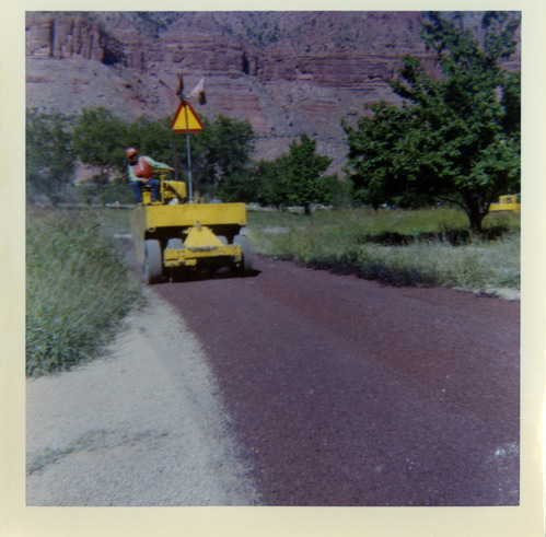 Man operating chipsealing machine to chipseal roads.