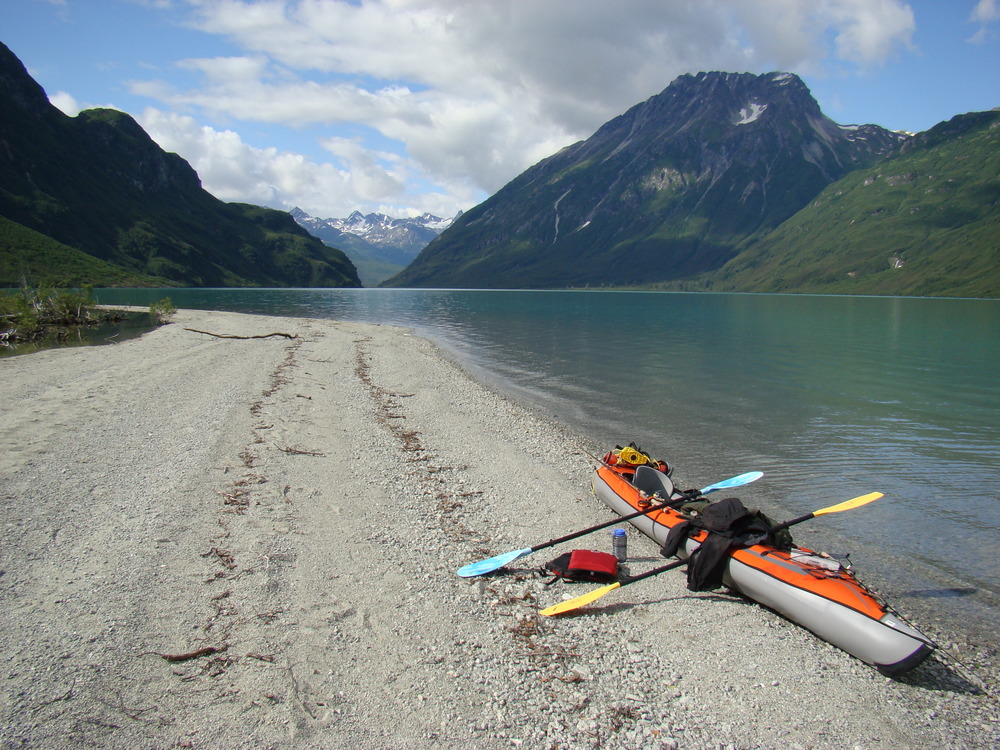 A kayak rests on the beach of Crescent Lake, pointed towards mountains rising from the water