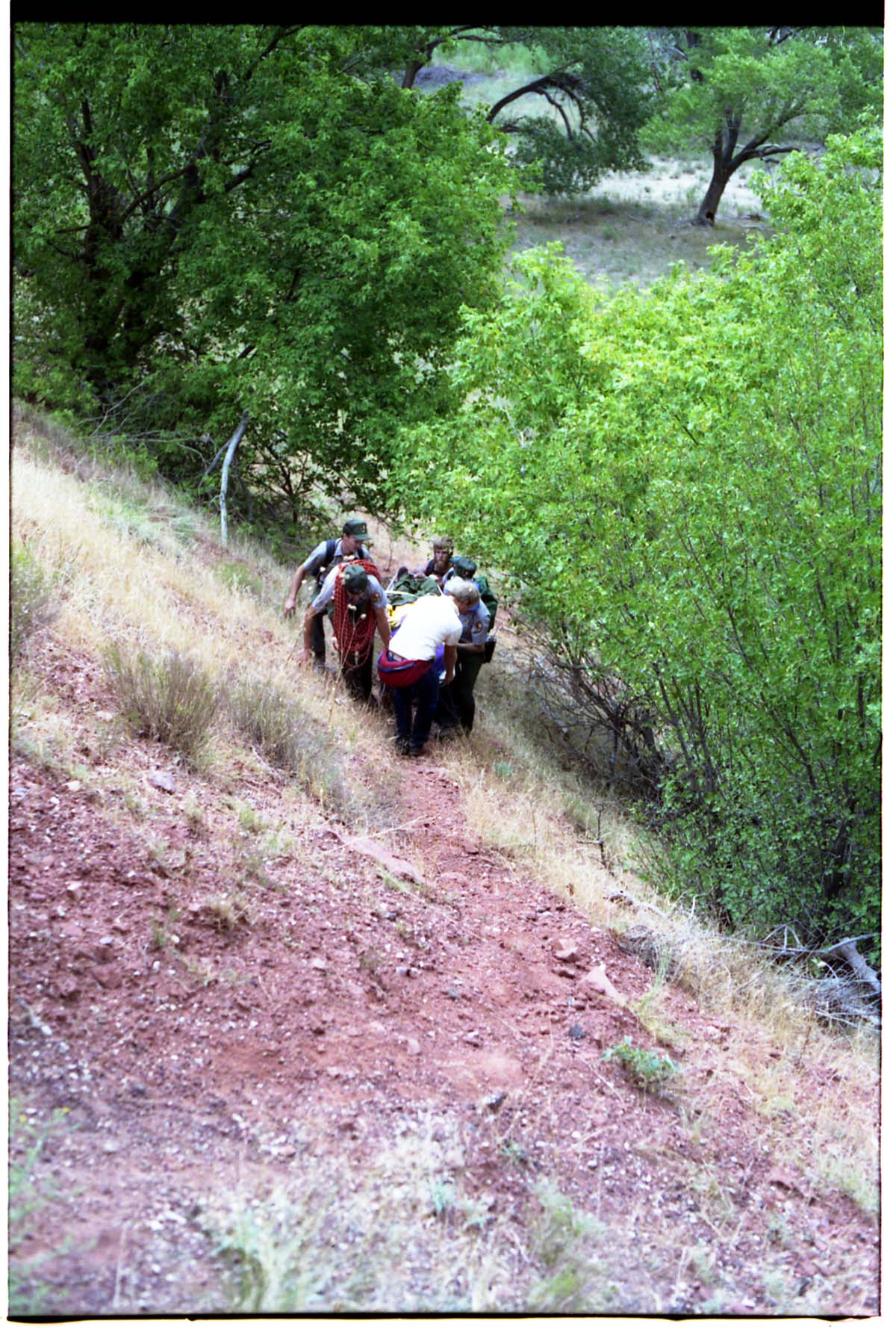 Color photo of SAR team transporting injured man.