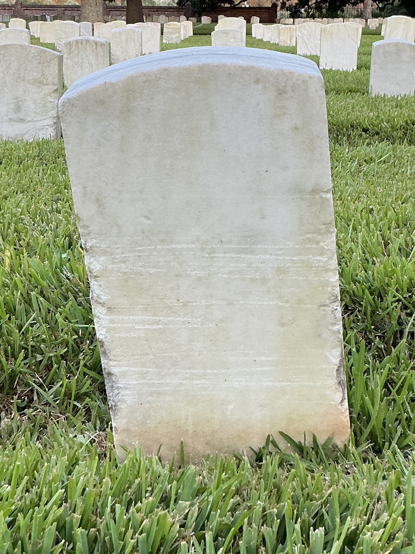 Back of historic upright marble headstone with recessed shield face.