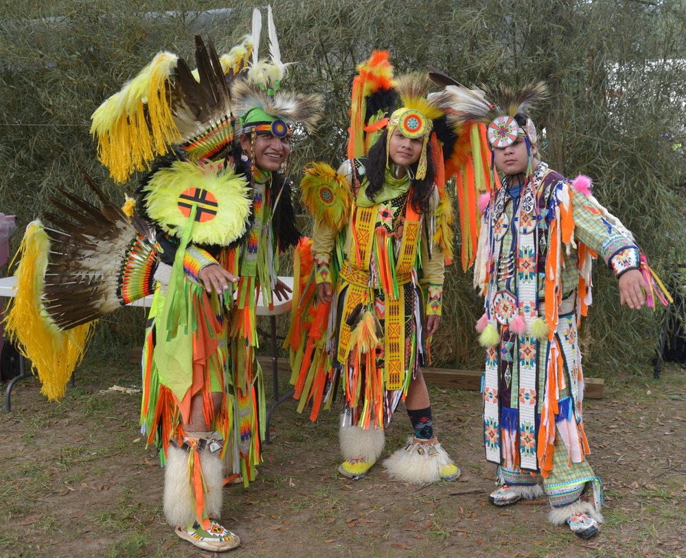 Muscogee (Creek) dancers in regalia posing for a picture.
