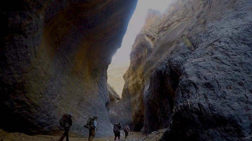 Backpackers explore the dark scenic passageway of Marble Canyon