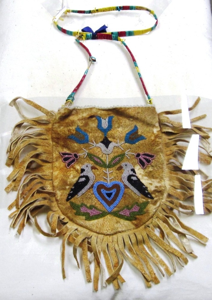 A rounded leather pouch with bird and floral beadwork design.