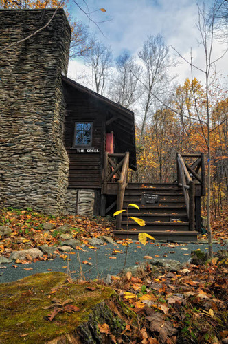 Large stony chimney on left, steps up to cabin entrance; fall color