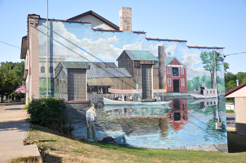 A building along the canal is painted with a large mural depicting canal life.