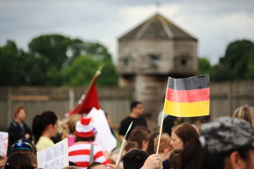 Students wave flags of many nations; bastion in background.