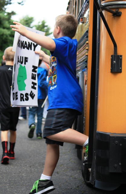 A student hops off the school bus, eager to start the parade.