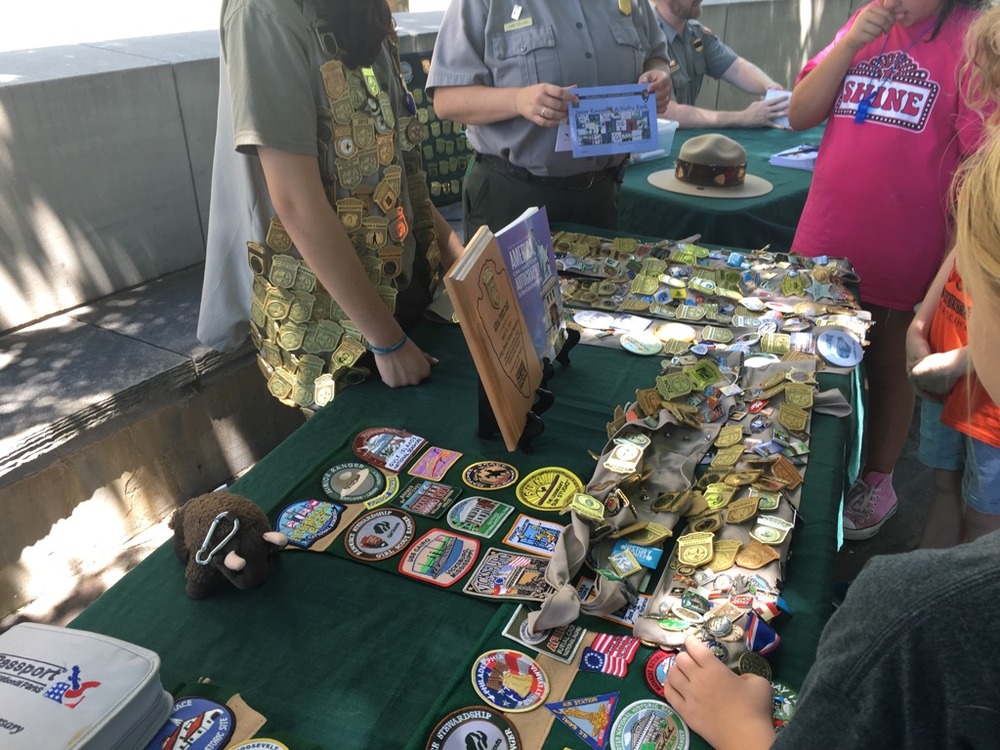 Girl standing behind table covered in junior ranger badges and patches.