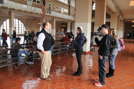 Film students with the “New Vision” communications class with New York State’s Greater Southern Tier schools shoot an interview about the bench project in the Great Hall at Ellis Island.