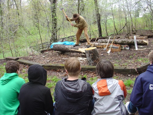 Costumed ranger demonstrating log hewing for school group