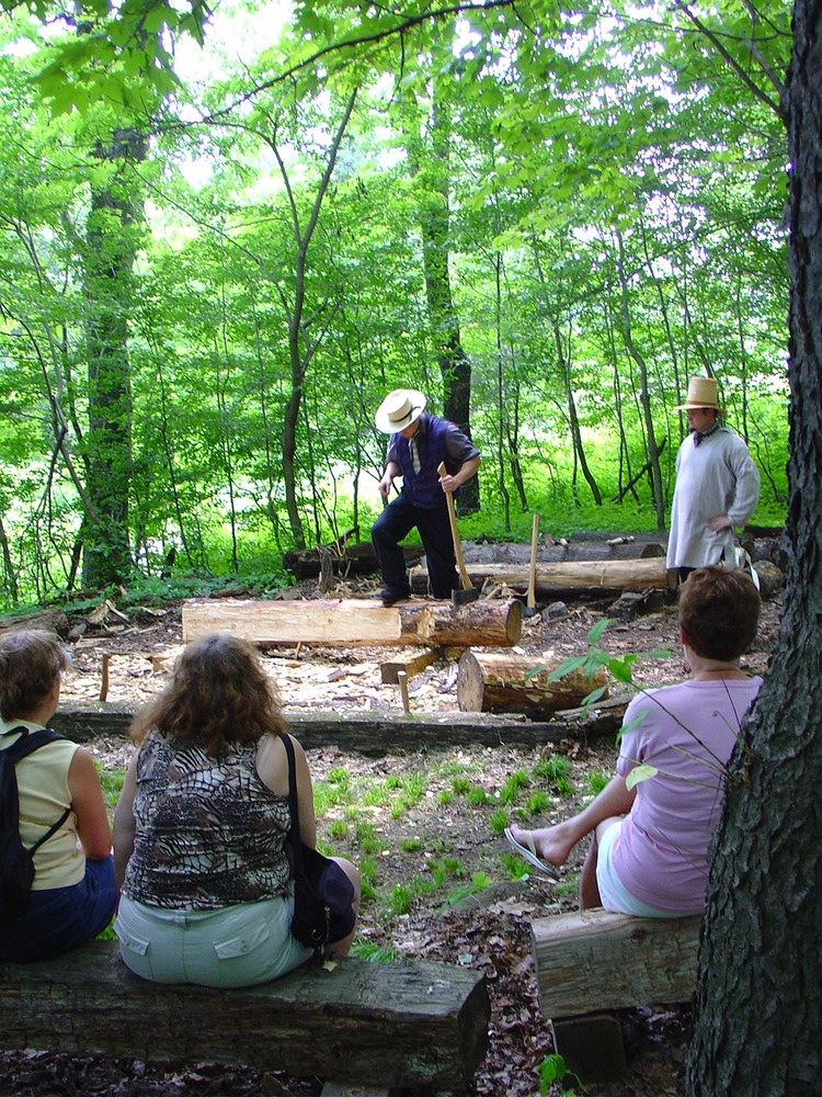 Costumed rangers demonstrating log hewing.