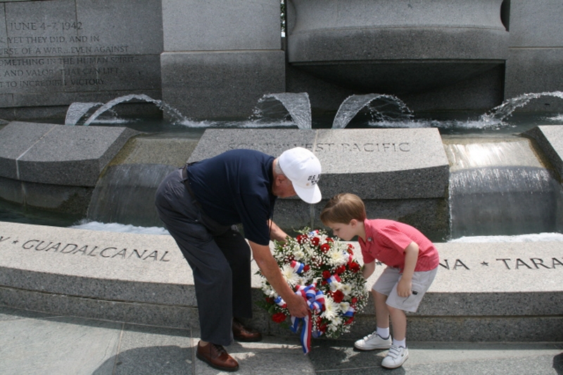 Man and boy place flowers at a monument