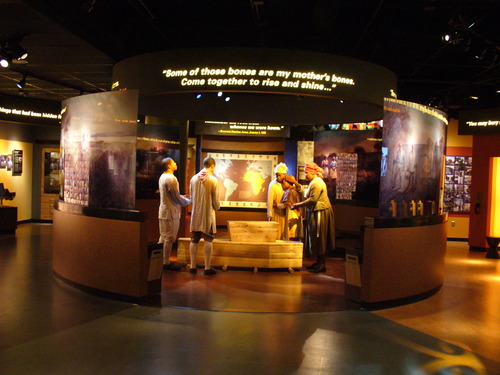 Models of slaves stand around a coffin in the visitor center exhibit