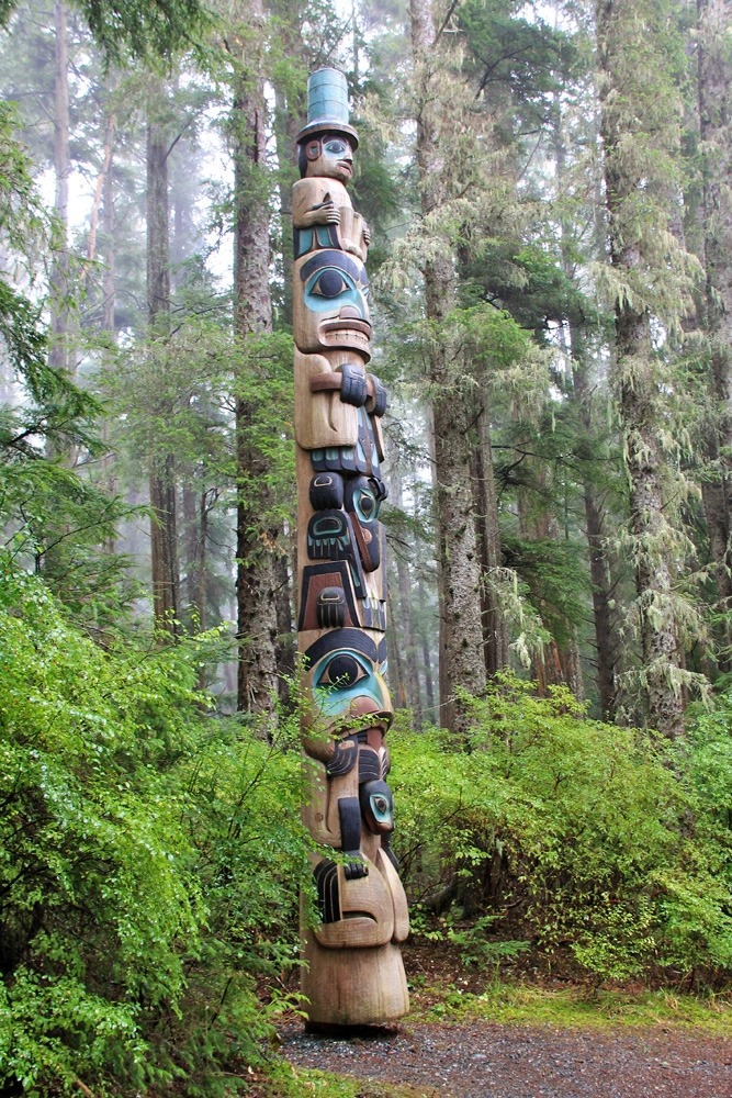 Totem pole with the Village Watchman on top wearing a tall conical hat.