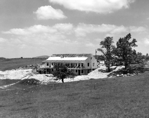 A large motel-type lodge is under construction, surrounded by mostly open landscape.