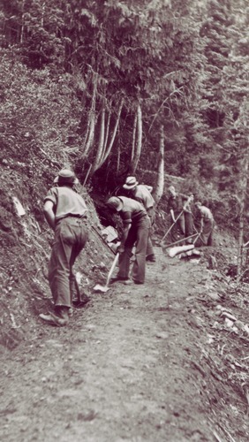 Black and white photo of a group of men with shovels working on a section of trail.