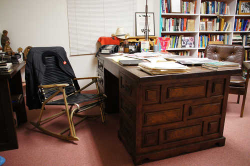 A simple chair with leather straps next to a desk and bookshelves