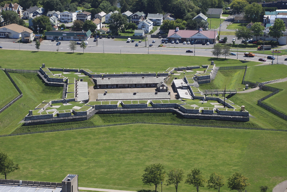 a green field with a grey and brown building in a star shape in the middle