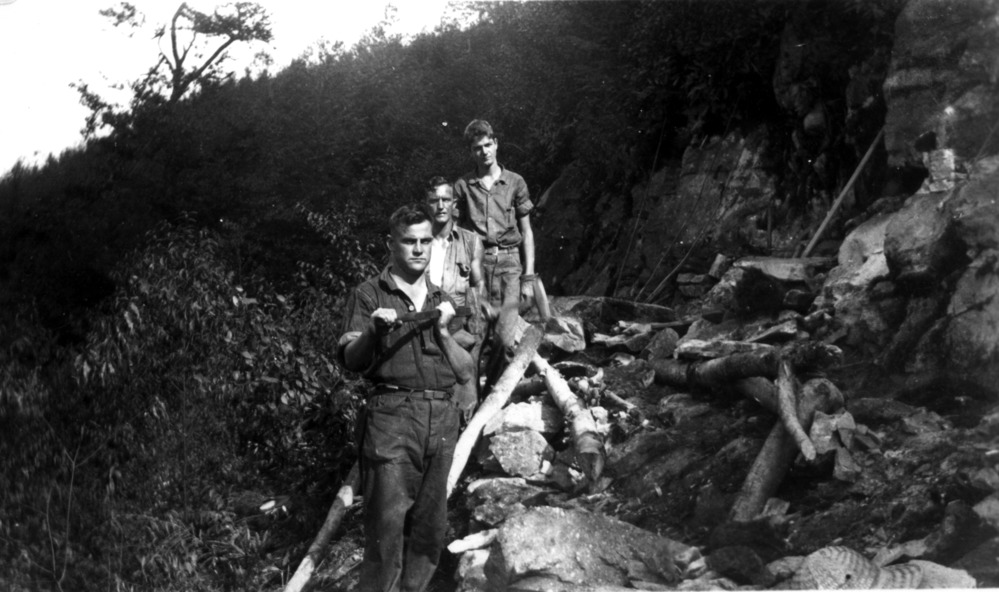 Three workers pause for a photograph along a trail that they are building