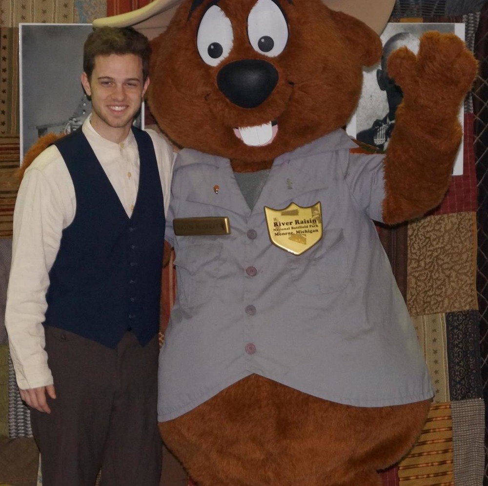 An actor posing with a beaver mascot. 