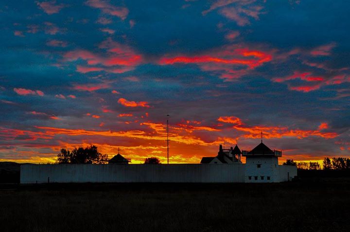 The sun has set and turned the clouds above the post an array of hues: red, pink, orange, and yellow. 