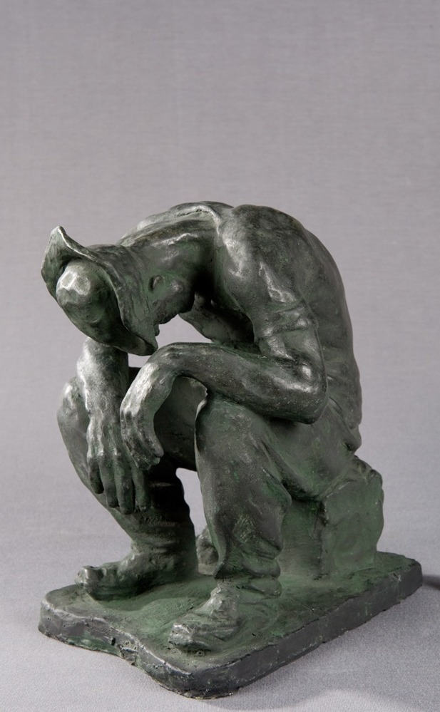A sculpture of man sitting on a box with his head hung.
