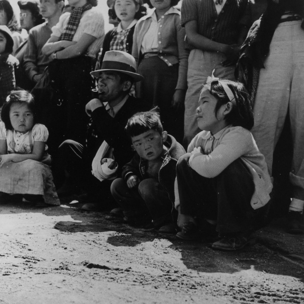 Evacuees of Japanese ancestry watching Memorial Day services. Evacue Boy Scouts took a leading part in the ceremonies held at this War Relocation Authority center