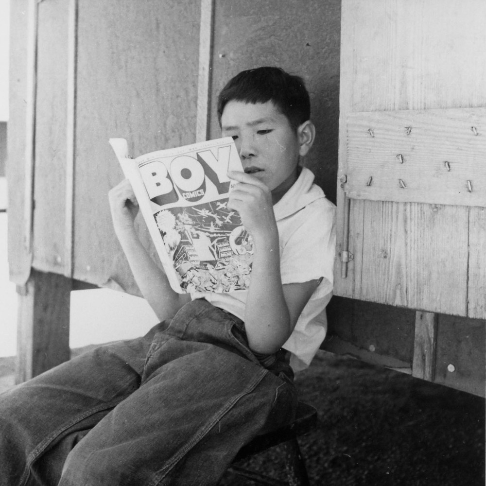 Evacuee boy at this War Relocation Authority center reading the Funnies.