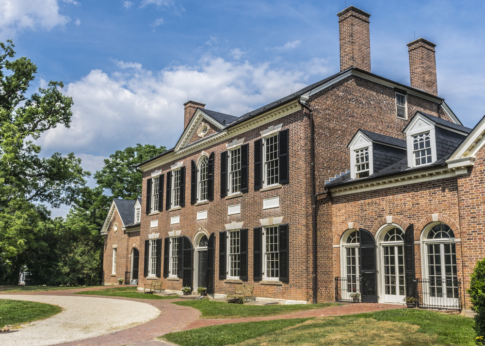 A stately red-brick mansion in the sun stands tall 