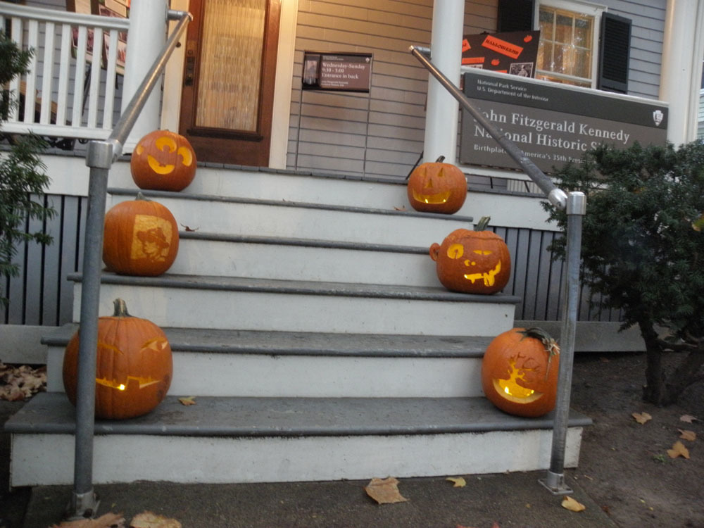 Six carved pumpkins sit on the stairs of 83 Beals Street. Some have funny faces; one is a tree, another is a park ranger.