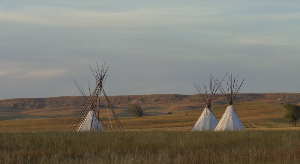 Early evening's golden daylight illuminates the tepees on the prairie north of Fort Union trading post.