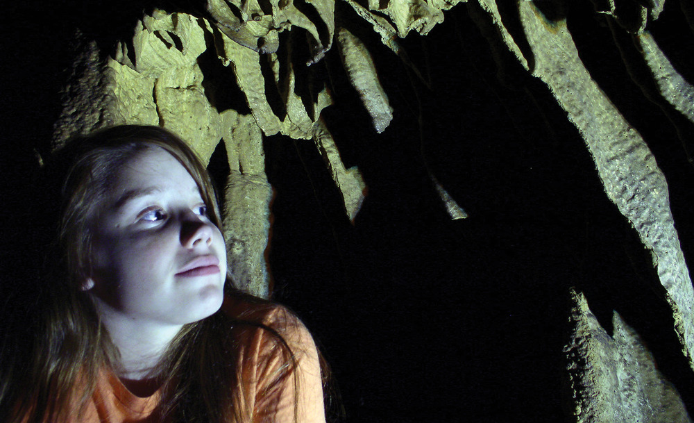 A girl peers into the shadows of Mammoth Cave, with an expression of wonder.