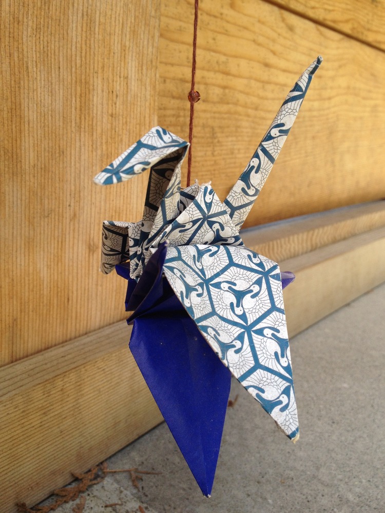 An origami paper crane is suspended from a string at the Memorial.
