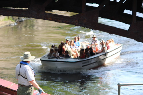 A man standing with his back to us watching a boat approach him