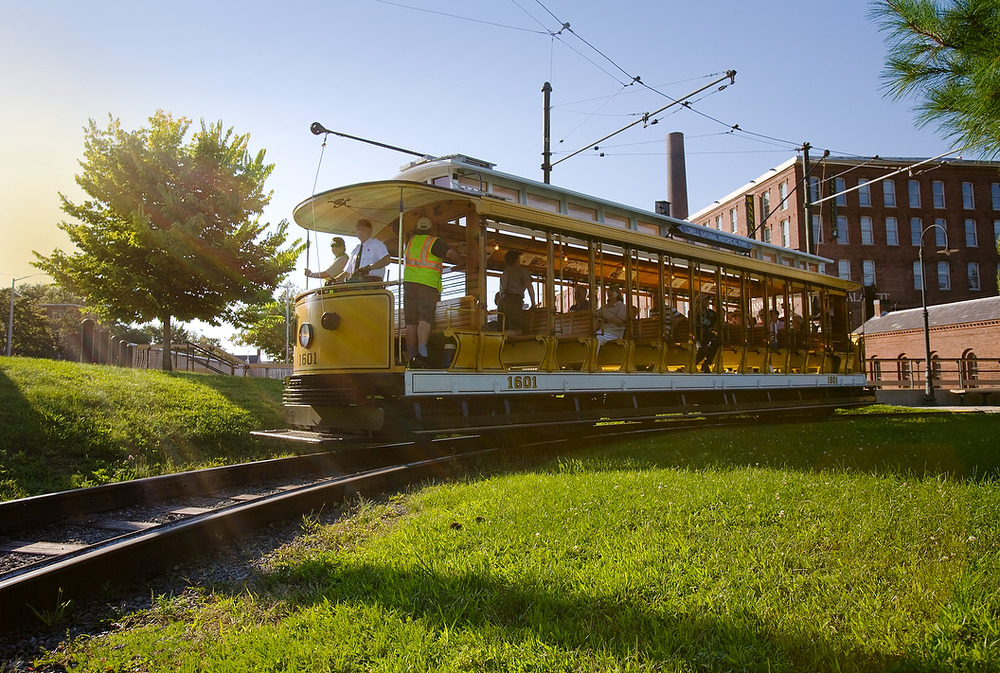 A trolley full of people turns a corner while a man drives it
