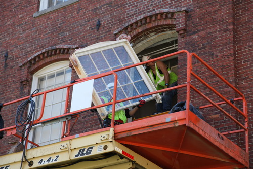Workers on a scaffolding outside the Boott Mills putting in new windows