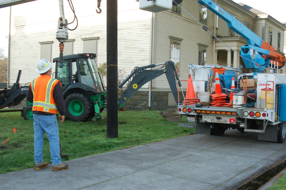 Image of utility truck lift with employee in raised basket conducting work on utility pole.
