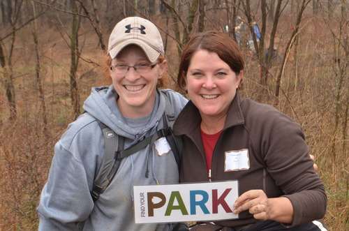 Two womoen outside holding a sign the says Find Your Park