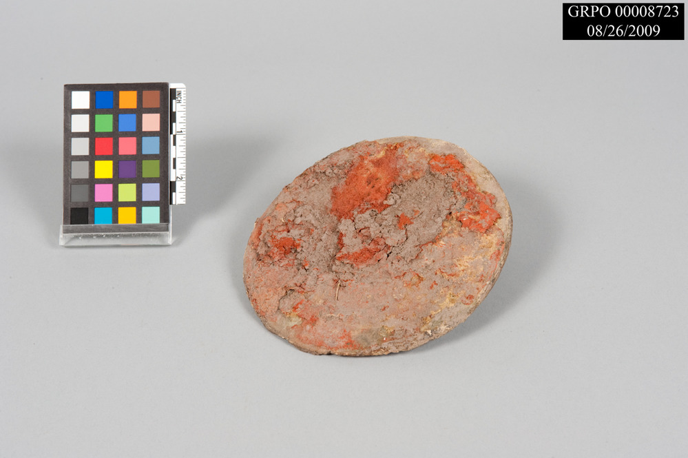 Round bucket bottom with soil and reddish-brown paint.