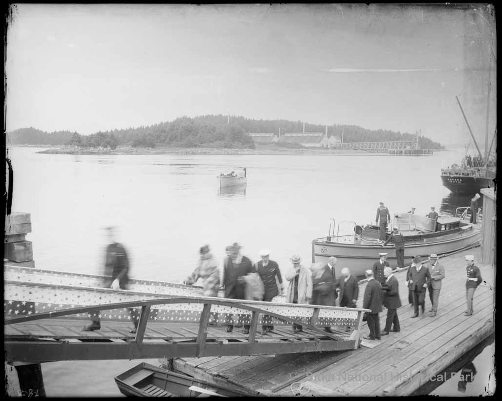 Group of people walking up a ramp from a boat dock.