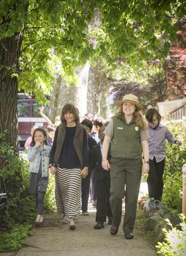 A teacher and a park ranger lead students down a tree lined street