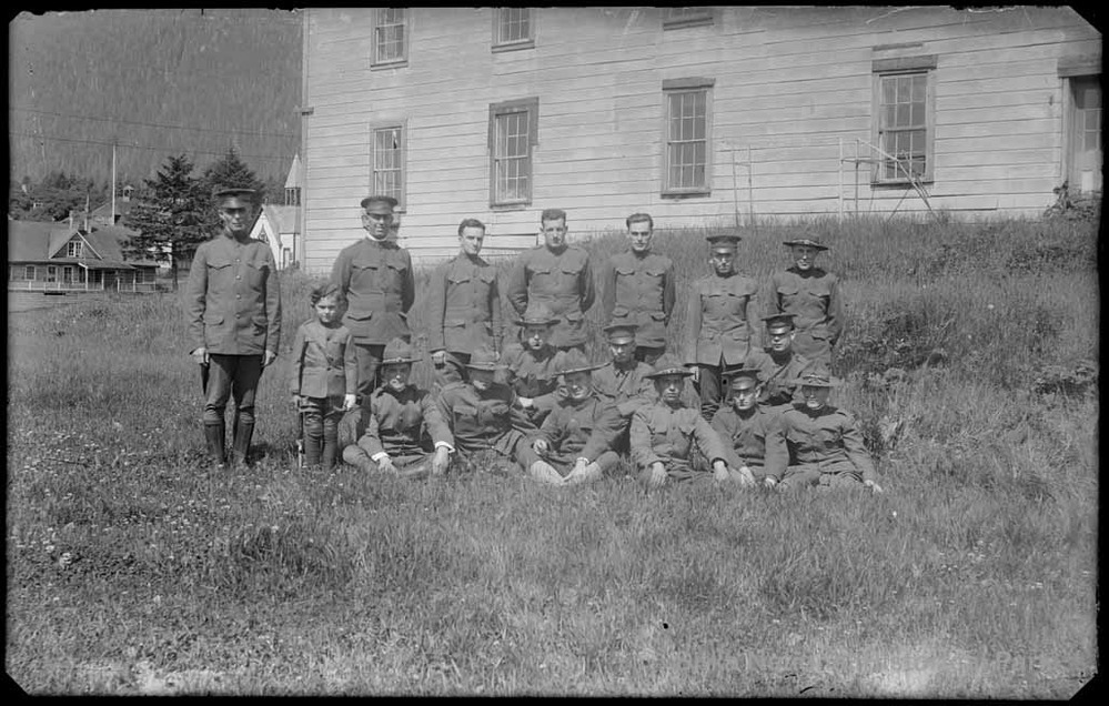Men in Sitka Signal Corps in World War I uniforms posing in front of a two story timber building.