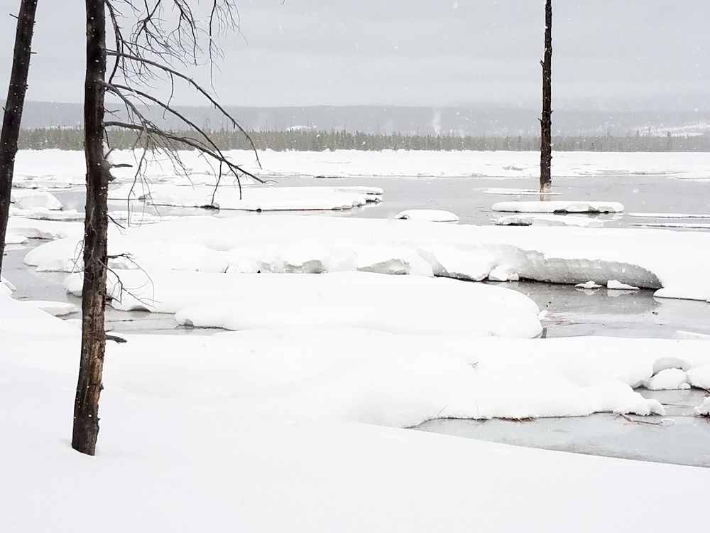 An expansive flat area has some snow and water in it.