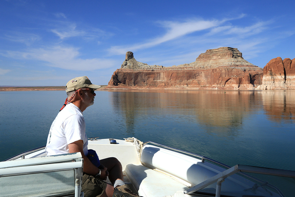  Man looks from back of small boat at Gunsight Butte