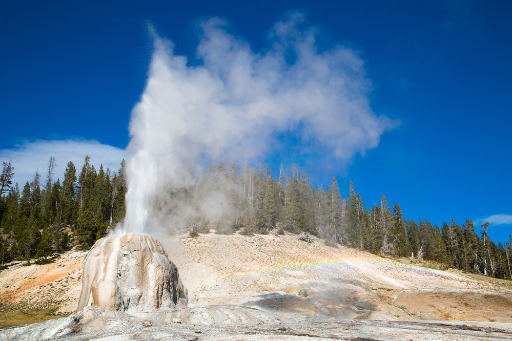 Water is erupting from a tall geyser cone.