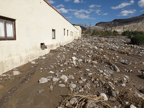 mud, rocks, and other flood debris washed up against the side of a building