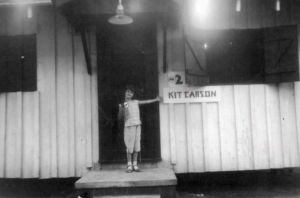 black and white photo of girl in cabin doorway