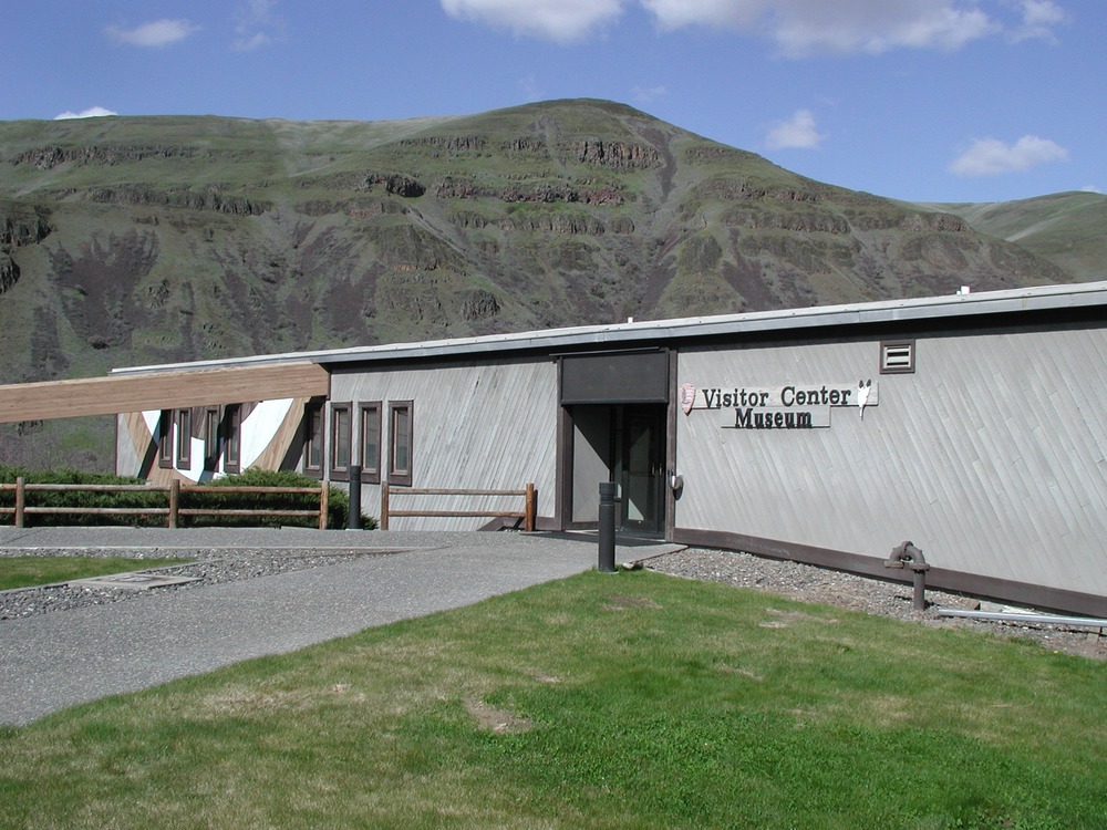 A grey one floor building with the sign 'Visitor Center and Museum' on it.